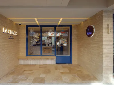 A cozy coffee shop with a brick wall, glass doors, and interior decor visible through the glass.