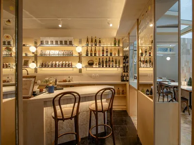A modern bar interior with wooden stools, concrete walls, and bamboo accents.