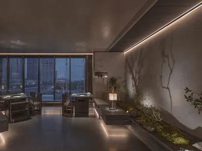 A modern restaurant interior with concrete walls and illuminated elements, featuring a central table for dining and a small g