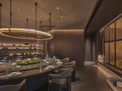 A modern restaurant interior featuring wood, glass, and metal elements.