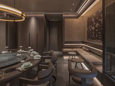Interior of a luxury dining room with dark wood accents, round tables, and modern seating arrangements.