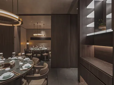 A modern minimalist restaurant interior featuring marble countertops, wooden tables, and glass accents.