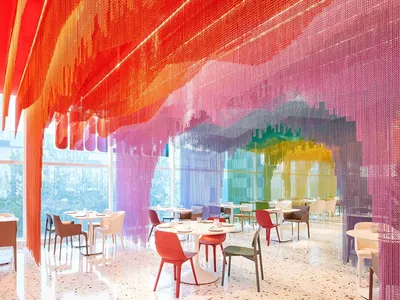 A modern restaurant interior featuring colorful drapes and bright lighting.