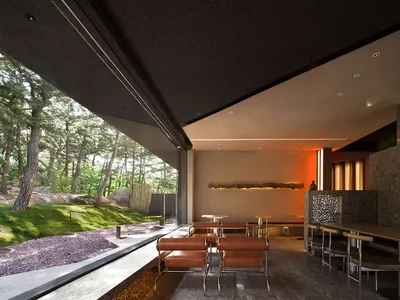 A modern restaurant interior with concrete walls and natural wood accents.