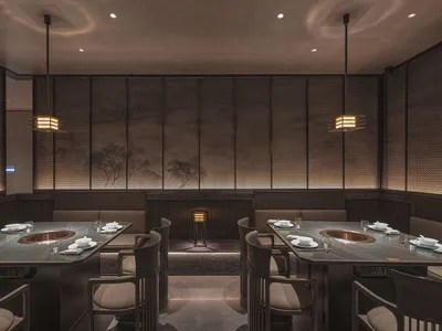 Modern restaurant interior with dark oak tables, white fabric seating, and minimalist lighting