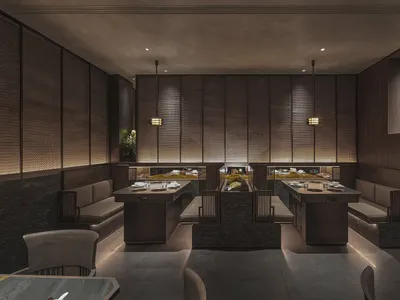 Modern restaurant interior featuring minimalist design with wooden seating and rock elements.