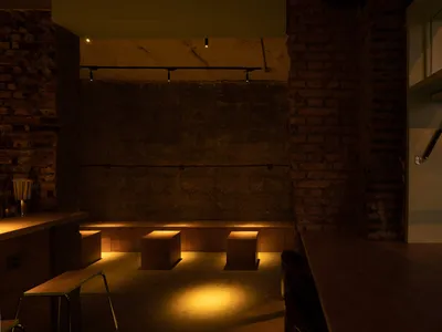 Interior of a restaurant bar featuring industrial design elements such as brick walls and concrete flooring.