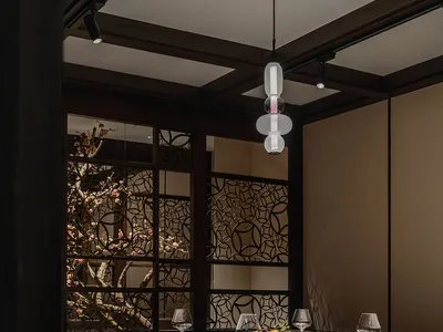 A luxurious restaurant interior with wooden accents, glass chandeliers, and elegant table settings.