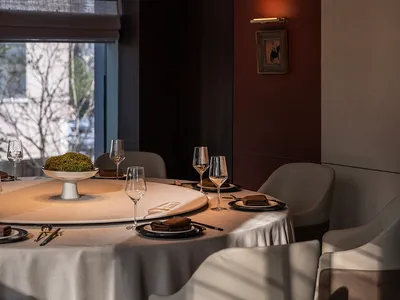 A modern restaurant interior with a round table, chairs, and decorative lighting.