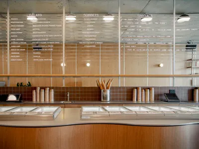 Modern restaurant interior with a wooden counter displaying ice cream flavors.