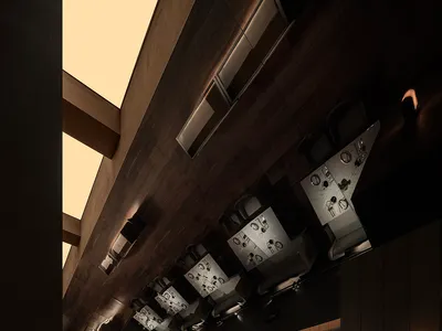 Modern restaurant interior with dark wood paneling and exposed beams on the ceiling.