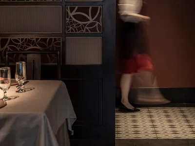 A table set in a modern restaurant with minimalist design features, including a glass wall and patterned wall.