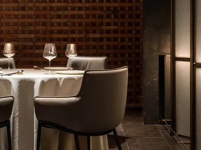 Dining room setting with brick accent wall, white tablecloth, and modern chairs.