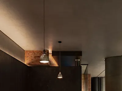 A modern restaurant interior showcasing sleek, concrete finishes with minimalistic design and warm lighting.