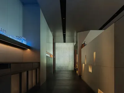 現代酒店走廊，混凝土牆面搭配玻璃欄杆。
