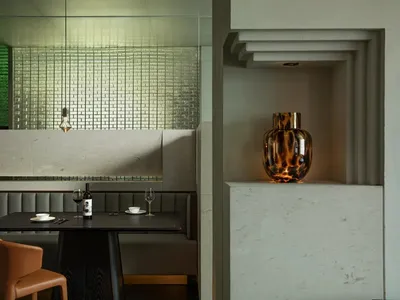 A modern restaurant dining space featuring a sleek table setting with a bottle of wine on a black table, accompanied by a vas