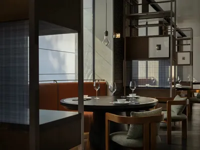 Modern industrial-style restaurant interior with round table, wine glasses, and modern seating.