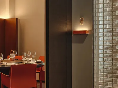 Modern restaurant dining room featuring glass walls, wooden accents, and leather seating.