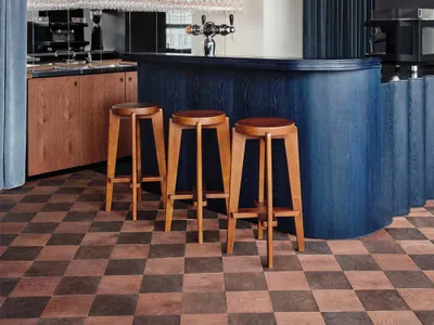 A modern bar with wooden stools, a blue curtain backdrop, and multiple glassware hanging above the counter.