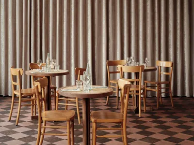 Modern restaurant interior with wooden furniture and checkered floor.