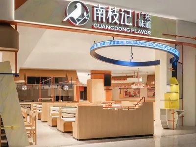 Modern food court interior with contemporary design elements, featuring tables, chairs, and signage.
