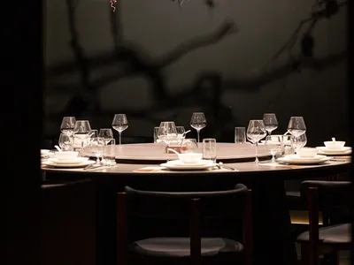 A modern restaurant setting with glass branches adorned with red pomegranates.