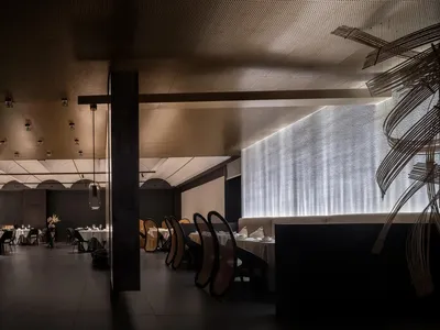 A modern restaurant interior with minimalist design elements, featuring contemporary furniture and lighting.