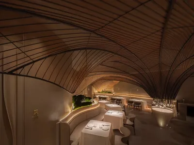 A modern restaurant interior with wooden arches and tables.