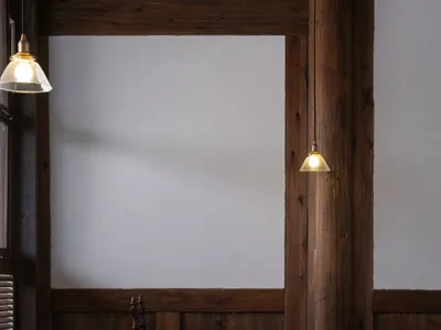 A cafe interior featuring wooden walls and tables, with pendant lights hanging above.