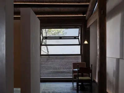 A minimalist restaurant interior with wooden elements and a large window.