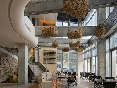 An industrial-style restaurant interior with concrete floors, walls, and hanging baskets.