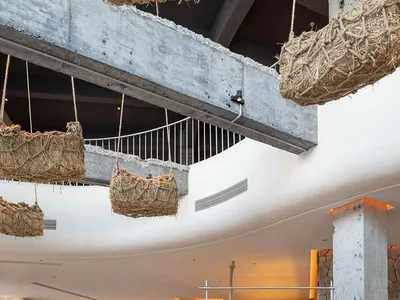 Concrete restaurant interior with industrial design, featuring wooden logs and concrete tables.