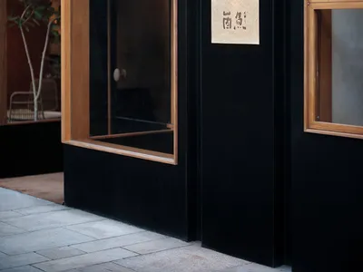 A modern restaurant storefront with black walls, orange accents, and large glass windows.