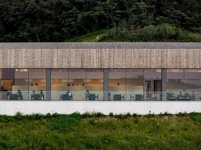 A modern restaurant interior featuring glass walls and a spacious, open design.