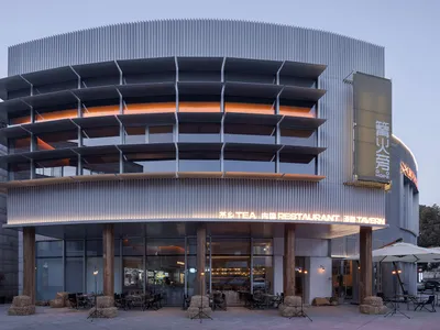 A modern restaurant exterior with metal cladding and illuminated signage.