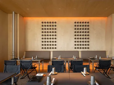 A modern restaurant dining area with wooden walls, metallic elements, and tables.
