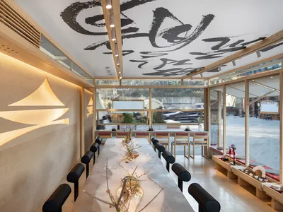 Modern restaurant interior with wooden tables, glass walls, and minimalist design features.