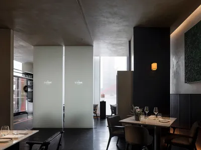 Modern restaurant interior with concrete walls, black marble accents, and minimalist design elements.