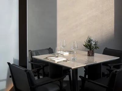 A minimalist restaurant interior with concrete and steel materials and elegant table setting.