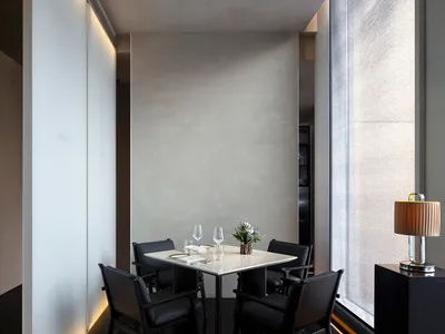 A minimalist restaurant interior featuring metallic accents, glass elements, and a minimalist design with concrete walls.