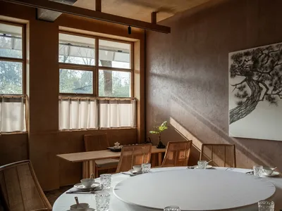 Industrial-themed restaurant interior with wooden furniture and large window.