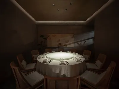 Modern restaurant interior with a round dining table, upholstered chairs, and soft lighting
