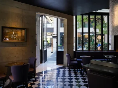 Modern interior of a restaurant with concrete walls, glass walls, and leather furniture.