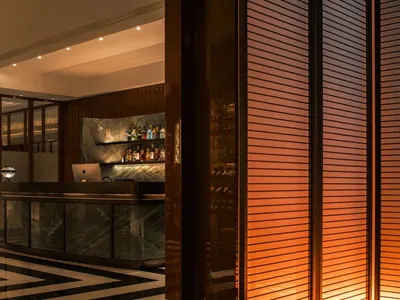 Interior design of a modern bar featuring a marble and concrete counter with glass elements.
