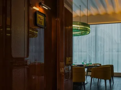 Modern restaurant interior with bold green lighting and black chairs.