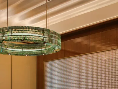 An industrial-style restaurant interior with black marble table, green glass chandelier, and green upholstered chairs.
