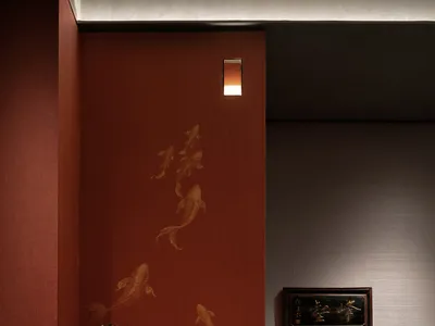Industrially styled restaurant interior with red wallpaper and painted gold fish