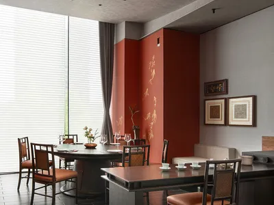 A modern dining room with wooden furniture and a red accent wall.