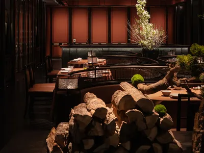 A modern restaurant interior with candlelit tables, wooden accents, and a cozy atmosphere.
