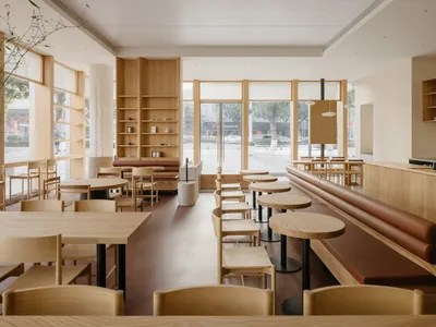 A modern restaurant interior featuring wooden furniture and minimalist design.